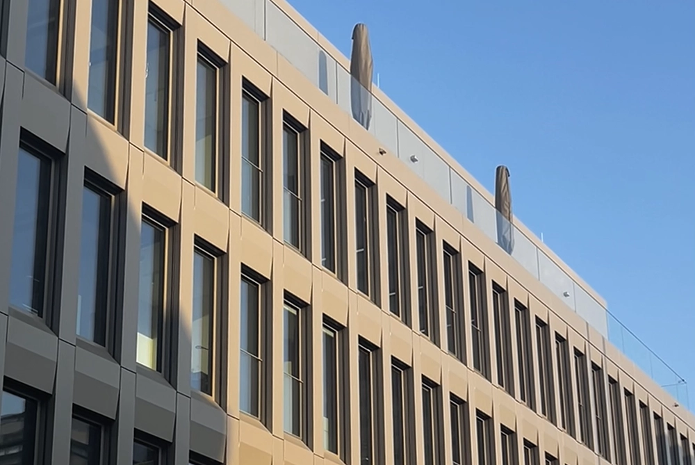 Zu sehen ist die Fassade des Bürogebäudes des Immobilienverwalters blauem Himmel.