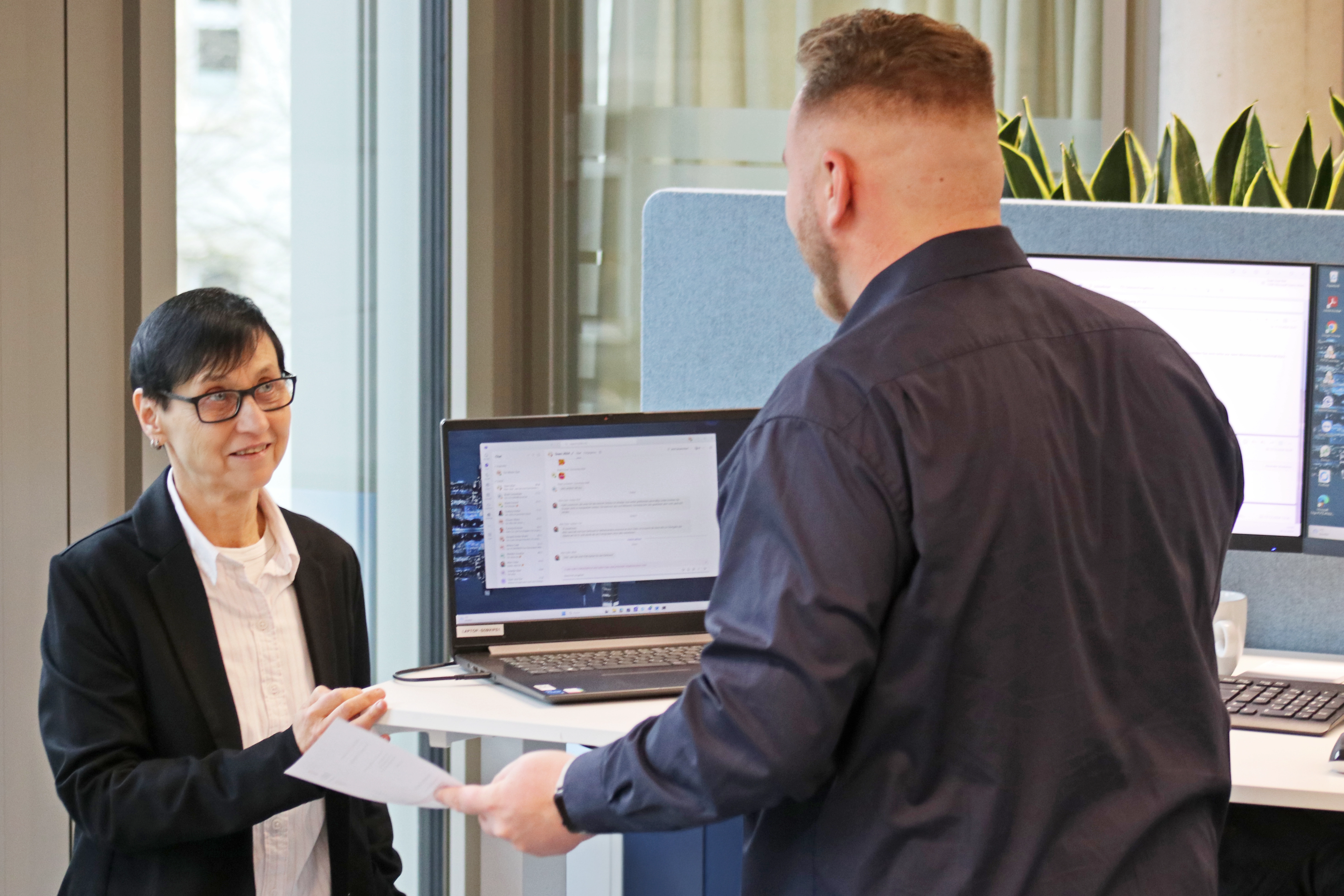 Beate Freund und Tim Winter unterhalten sich über ein Projekt am Arbeiztsplatz