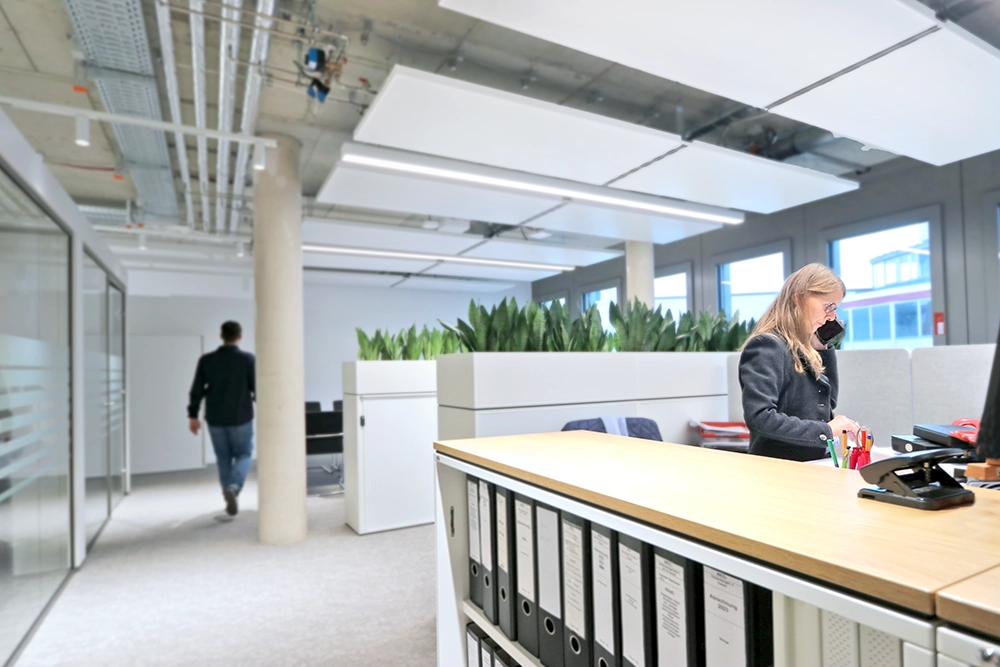 Eine Mitarbeiterin steht teleonierend am Arbeitsplatz.