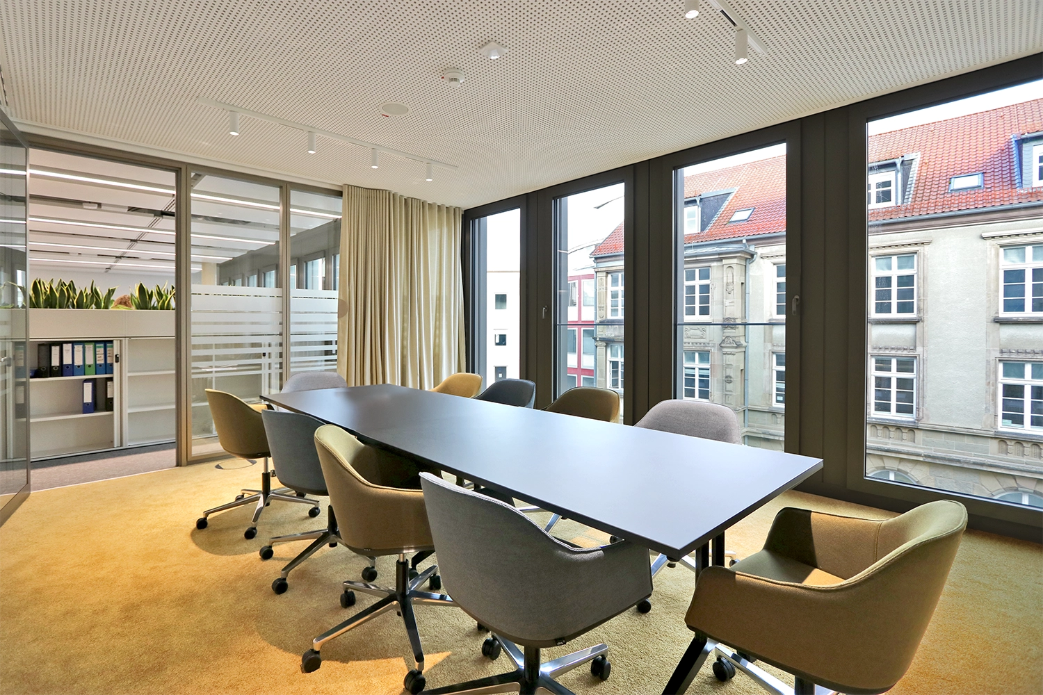 Der Besprechungsraum mit großem Tisch und Fensterfront im Hintergrund.